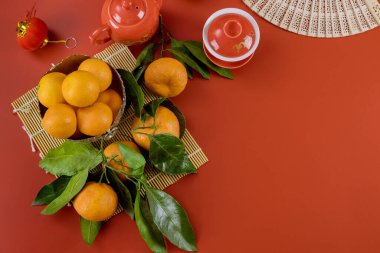 Asya Yeni Yıl kutlamaları bambu ve mandalina üzerine çay setiyle kırmızı arka planda bir Asya Yeni Yıl kutlamaları