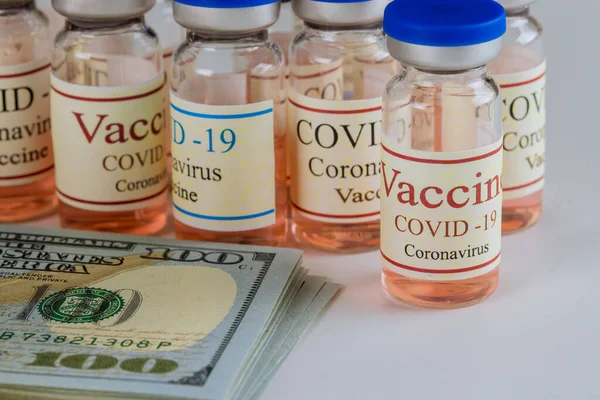 Vials glass bottle of American vaccine Sars-Cov-2, COVID-19 Coronavirus with dollars many US bills of the USA flag in the background