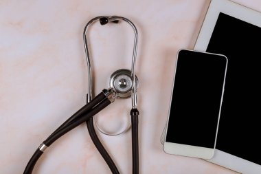 Tıbbi steteskobu mermer masanın üzerinde olan dijital tablet bilgisayardaki işyeri hastane ofisi.