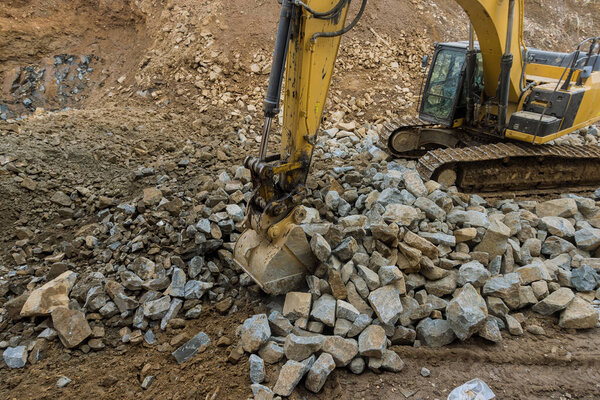 Подготовка к работам по строительству дорожного экскаватора с камнем на незавершенном участке для переработки