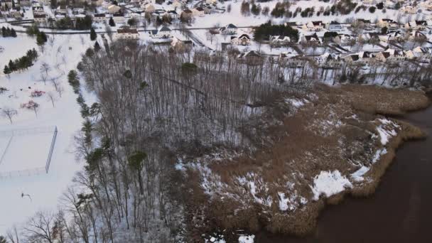 Vue aérienne vers le bas sur les maisons individuelles couvertes et les routes à la saison d'hiver cours couvertes de neige — Video