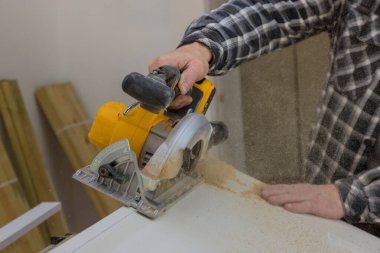 Marangoz ahşap kapıyı kesmek için el testeresi kullanıyor.