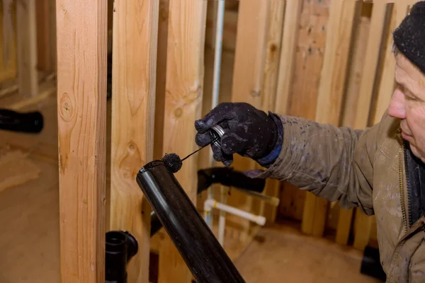 Encanador juntando tubos de drenagem de esgoto de PVC em uma casa em construção — Fotografia de Stock