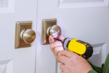 Çilingir işçisi eve yeni bir sahte kilit takıyor.