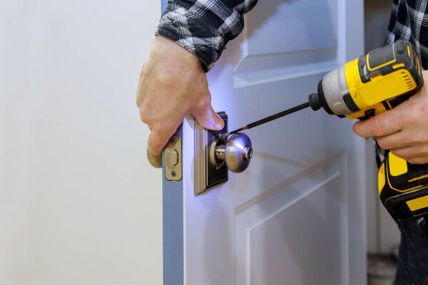 Master with screwdriver installs access the room door new lock in house.