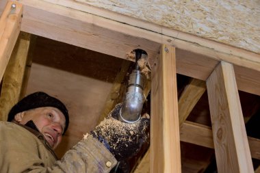 İnşaat işçisi kanalizasyon borularının kirişinde delik açıyor. Tesisat giderleri için delik açıyor.