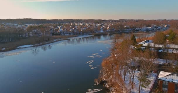 Luftaufnahme von Wohnhäusern bedeckt Schnee bei Landschaft Blick auf das Ufer des Flusses schwimmendes Eis treibenden frühen Frühling Überschwemmungen mit Schnee auf bedeckten Häusern und Straßen. — Stockvideo