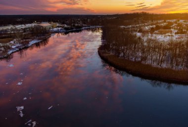 Hava manzaralı turuncu gün batımı. Şehir üzerinde nehir boyunca güneş ışığı. Özel evlerin yerleşim alanlarıyla birlikte.
