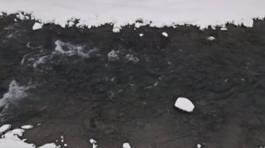 Karlı kış manzarası, çözülmemiş nehir, karla kaplı dalları olan köknar ormanı.