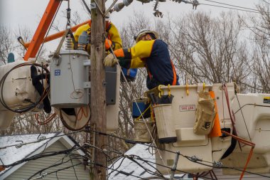 10 Şubat New York NY ABD: Elektrikçi tulumuyla kar yağdıktan sonra elektrik kabloları yüksek ve tehlikeli bir şekilde çalışıyor ve kovayla su üzerinde çalışıyor.