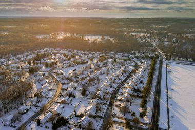 Amerika 'nın barışçıl kar manzarası. Kış günbatımı manzarası. Kar yağdıktan sonra küçük bir kasabanın evleri ve caddelerinde.