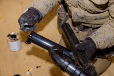 Tesisatçı elleri yapıştırıcı ile iki parça plastik drenaj PVC boru, yeni banyo kapağı