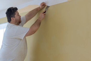 Ev onarımına hazırlanıyorum. El, eski duvar kağıdını söküyor.