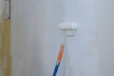 İşçi duvarları boyuyor, apartman tadilatı yapıyor, evi tamir ediyor boya rulosu yapıyor.