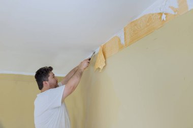 Tamirat odasındaki onarımlar sırasında duvardaki eski duvar kağıtlarını sökmeye hazırlanıyorlar.