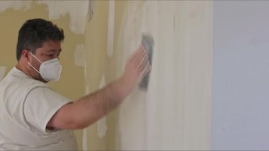 Müteahhit, alçı levhayı zımparalayarak kum malası kullanıyor.
