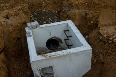 Yol inşaatı alanında kurulu su drenajının montajı. Kare beton rögar kapakları.