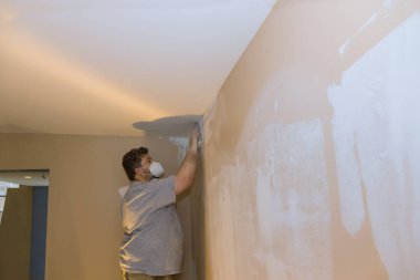 İşçi alçı levhayı alçıpanla zımparalayarak düzeltiyor ve bitiriyor