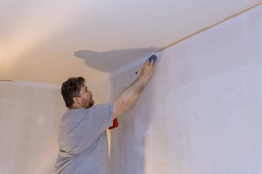 Profesyonel ressam, duvara boya sürmek için fırça kullanıyor.