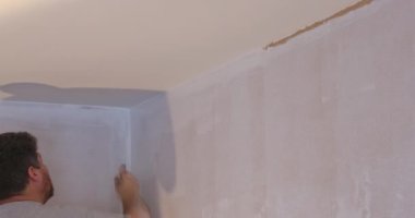 Ev dekorasyonu. Kapalı alanda çalışan fırça boyacısı kullanarak duvarlara boya sürmek.