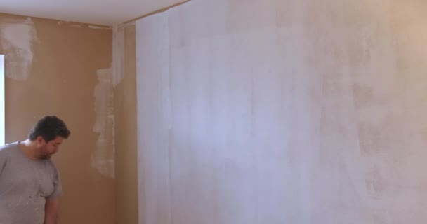 Vista trasera del pintor pinta la pared con un rodillo — Vídeos de Stock