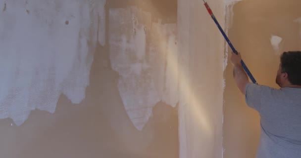 Художник заґрунтував стіну грунтовкою для ремонту стіни після нанесення гіпсової штукатурки . — стокове відео