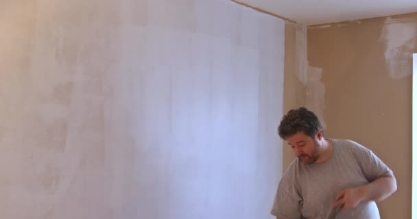 Trabajador cebado con un rodillo de pintura con reparación de la pared después de aplicar yeso para trabajos de interior — Vídeos de Stock