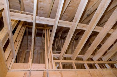 İnşaat kirişleri altında ahşap çerçeveli bir ev evin çatısını döşemiş.