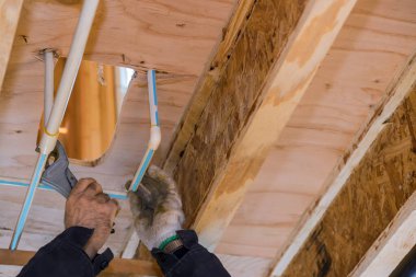 Tesisatçı müteahhit PVC boru kesici polipropilen boru makasla yeni evdeki su borusunu kesmek için beyaz eldivenli el işçisi.