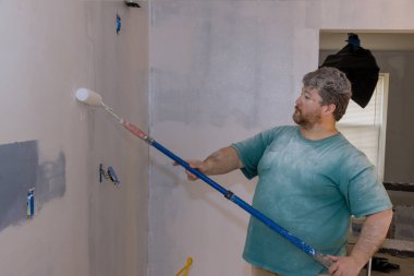 İşçi duvarları boyuyor, apartman tadilatı yapıyor, evi tamir ediyor boya rulosu yapıyor.