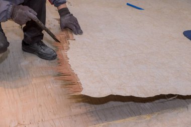 İşçi eski muşamba döşemeyi ev tadilatıyla söker.