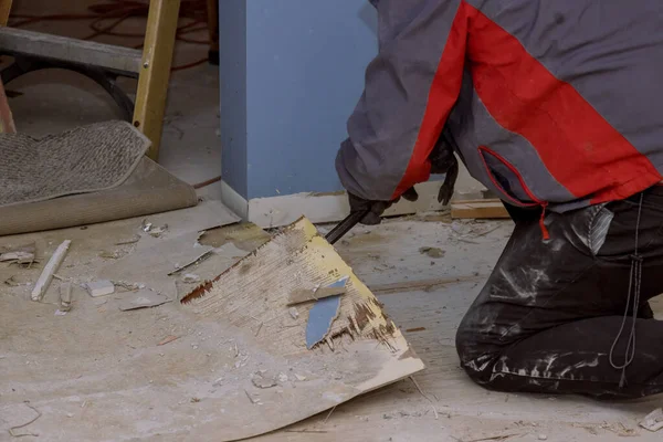 Handyman during work of removing old laminate flooring with preparing restoration old house