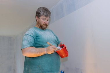 Duvarları boyamaya hazırlanırken boya ve fırça tutacağı için kırmızı boya bardağı