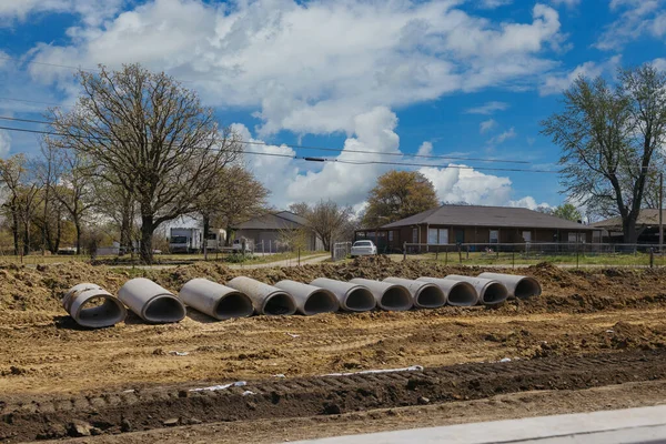 地上のコンクリート下水道管のスタック地下設置のための準備青空の背景にビュー建設道路の場所 — ストック写真