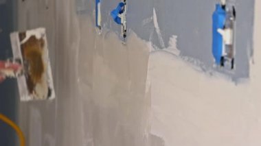 Duvarı spatulayla hizalayan adam macun ve spatula duvarıyla çalışıyor.