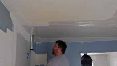 İşçi, boya spatulası kullanarak duvarı yerleştirmiş.