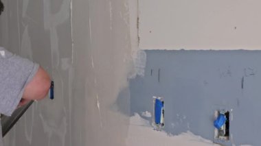 İşçi, boya spatulası kullanarak duvarı yerleştirmiş.