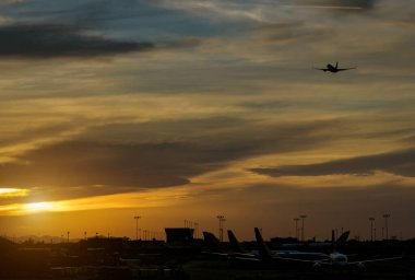 Gün batımında pist işaretleri silueti gökyüzü kırmızı bulutlar uçak kalkışı sırasında havaalanı bulutları