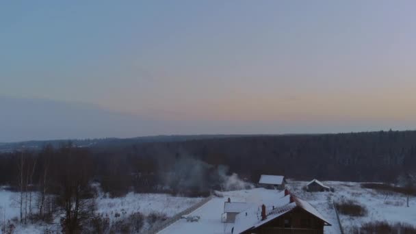 Puesta de sol en el paisaje de invierno, hermosa casa en el pueblo el humo proviene de la chimenea — Vídeo de stock