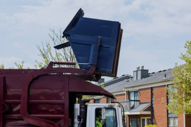 Garbage collection in the courtyards of residential buildings the garbage truck prepares to take in garbage bins inside