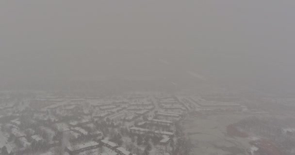 Χειμώνας κατά τη διάρκεια της ημέρας χιονόπτωση στέγη σπίτια χιονισμένα δέντρα κάλυψε τη θέα χιονισμένο με κατοικημένη μικρή πόλη — Αρχείο Βίντεο