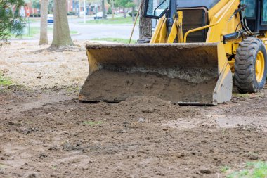 Buldozer hareket ediyor, yerdeki inşaat alanında kürekleri kullanarak zemini düzleştiriyor.