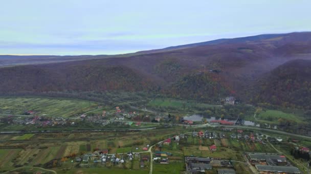 Вид с воздуха в горной долине осенний пейзаж с небольшой деревней — стоковое видео