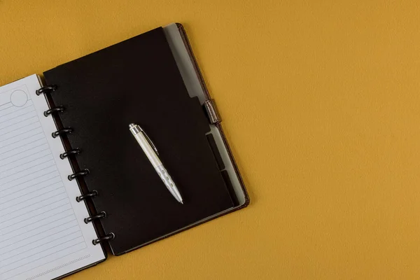Office desk top view with pencil and blank notebook on yellow background