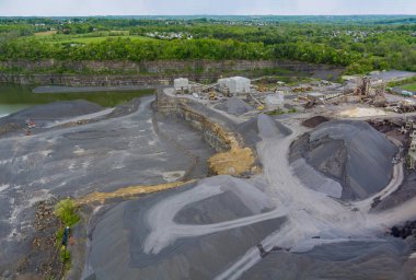 Panorama hava manzaralı açık çukur mayını taş ocağı endüstrisinin çeşitli katmanlarını açık döküm madenciliğinde bir sürü makineyle gösteriyor.