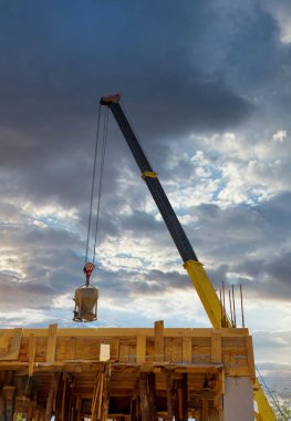 Tel vinçle asılı beton kovalı ağır inşaat makineleri.