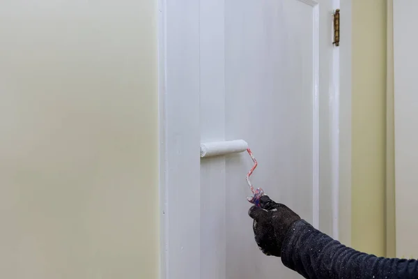 Handyman home renovation painter of painting doors trim using hand roller painting with gloves