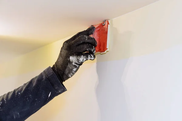 Home renovation on working contractor user in corner paint edger brush painter hands in the painting the wall