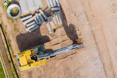 Küçük kazıcının inşaat alanındaki apartmana beton kanalizasyon borusu yığılmış.