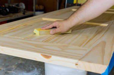 Marangoz zımparalanan zımparalanan zımparalanan tahta iç kapılar üzerinde çalışıyor.